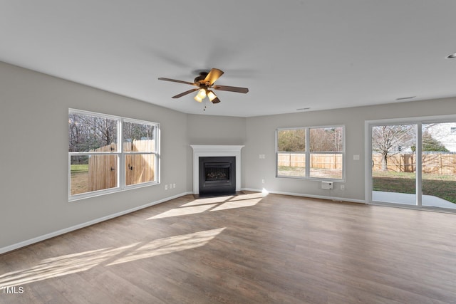 unfurnished living room with a fireplace with flush hearth, ceiling fan, baseboards, and wood finished floors