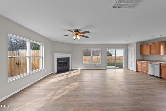 unfurnished living room featuring visible vents, baseboards, a fireplace with flush hearth, light wood-style floors, and recessed lighting