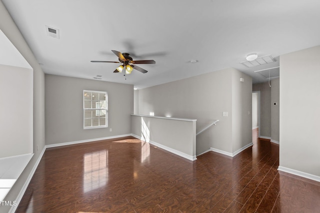 unfurnished room featuring visible vents, wood finished floors, attic access, and baseboards