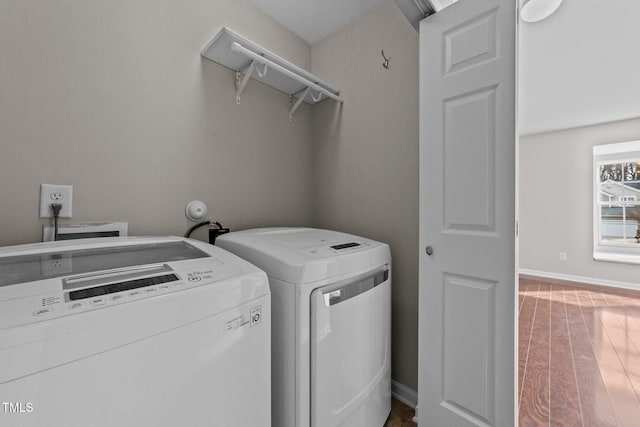 washroom with washing machine and dryer, laundry area, baseboards, and wood finished floors