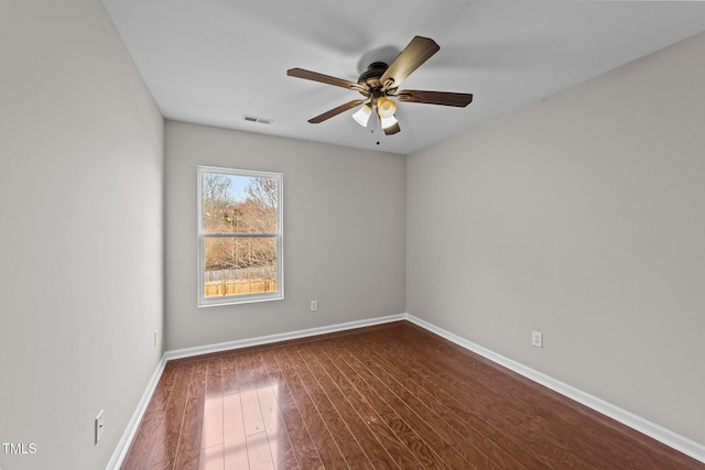 unfurnished room featuring a ceiling fan, visible vents, dark wood finished floors, and baseboards