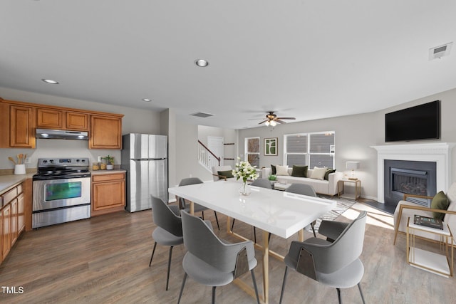 kitchen featuring under cabinet range hood, visible vents, stainless steel appliances, and dark wood finished floors