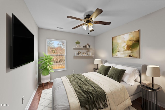 bedroom featuring baseboards, visible vents, ceiling fan, and wood finished floors