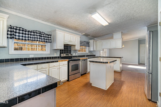 kitchen featuring a center island, white cabinetry, ornamental molding, and appliances with stainless steel finishes