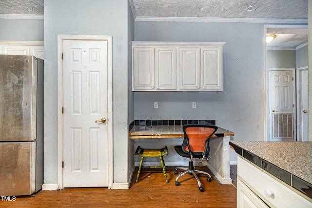 office featuring hardwood / wood-style flooring, a textured ceiling, crown molding, and built in desk