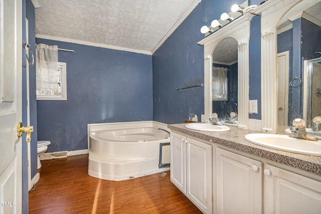 bathroom with toilet, hardwood / wood-style floors, a textured ceiling, a tub to relax in, and ornamental molding