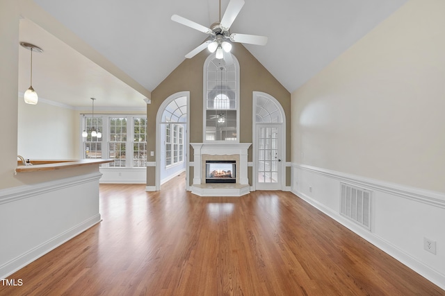 unfurnished living room with a multi sided fireplace, high vaulted ceiling, light wood-type flooring, and ceiling fan