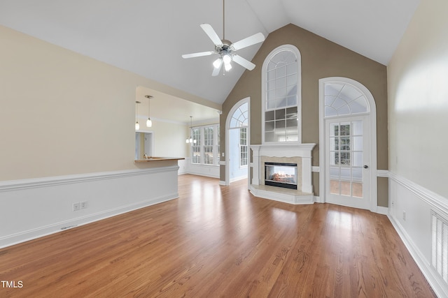 unfurnished living room with ceiling fan, high vaulted ceiling, and light wood-type flooring