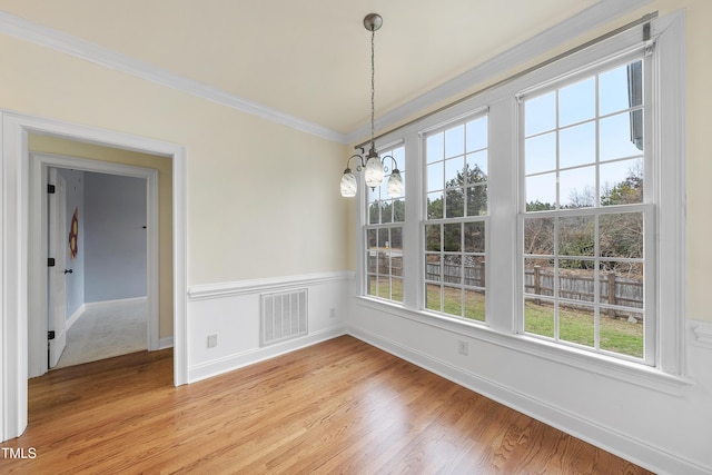 unfurnished dining area featuring crown molding, a chandelier, and light hardwood / wood-style floors