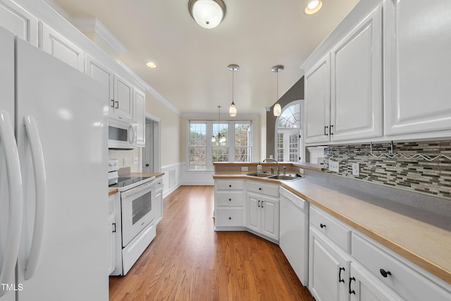 kitchen with sink, tasteful backsplash, hanging light fixtures, white appliances, and white cabinets