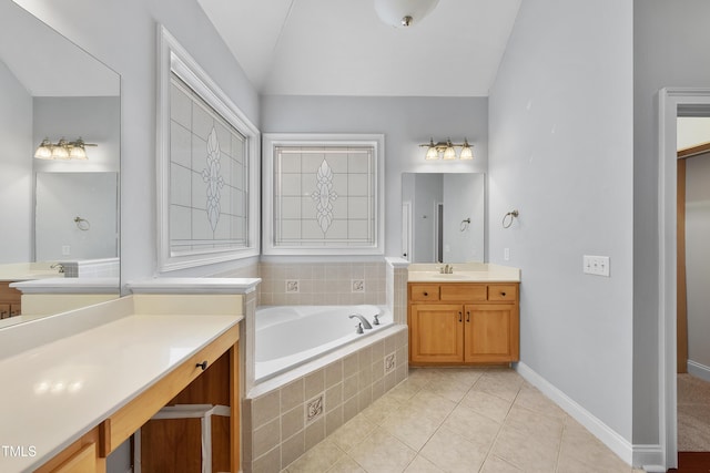 bathroom with tile patterned flooring, vanity, a relaxing tiled tub, and vaulted ceiling