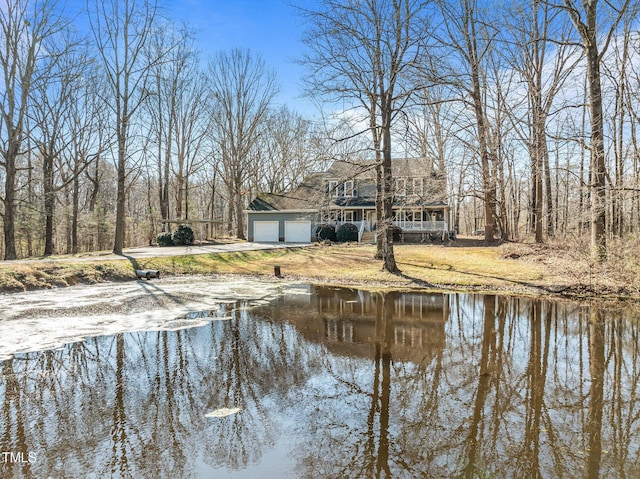 view of yard featuring a garage, driveway, and a water view