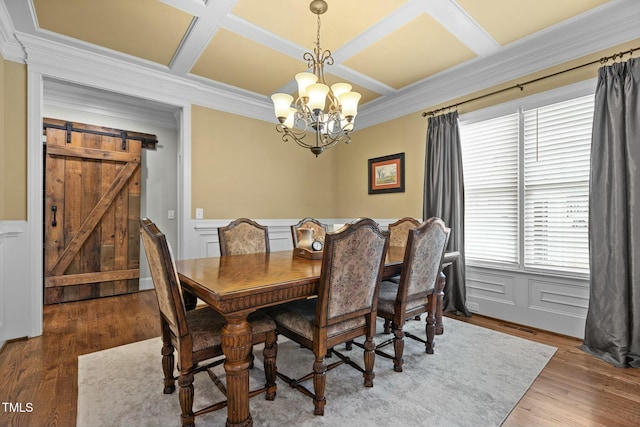 dining room with an inviting chandelier, hardwood / wood-style floors, coffered ceiling, ornamental molding, and a barn door