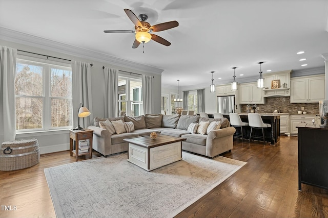 living room featuring crown molding, ceiling fan with notable chandelier, and hardwood / wood-style flooring