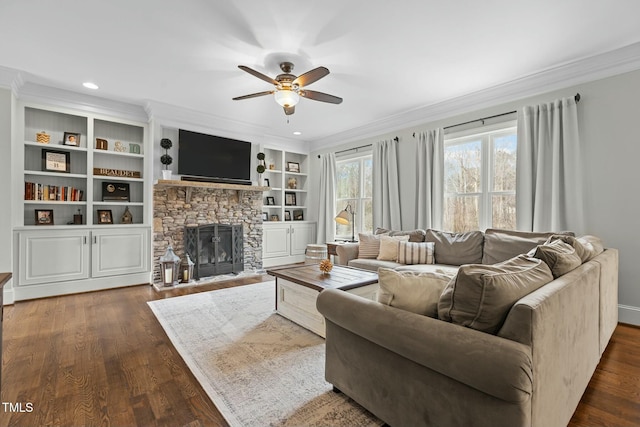 living room featuring ornamental molding, a stone fireplace, built in features, and ceiling fan