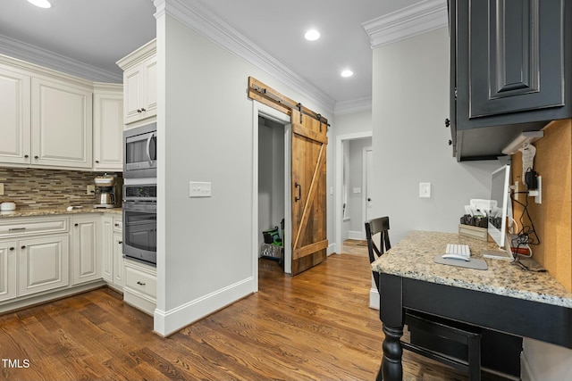 kitchen with light stone counters, ornamental molding, appliances with stainless steel finishes, dark hardwood / wood-style floors, and a barn door