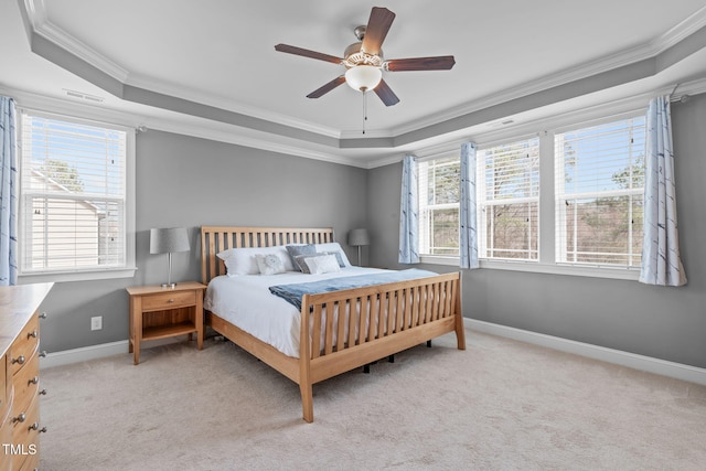 bedroom with a tray ceiling, multiple windows, and light colored carpet