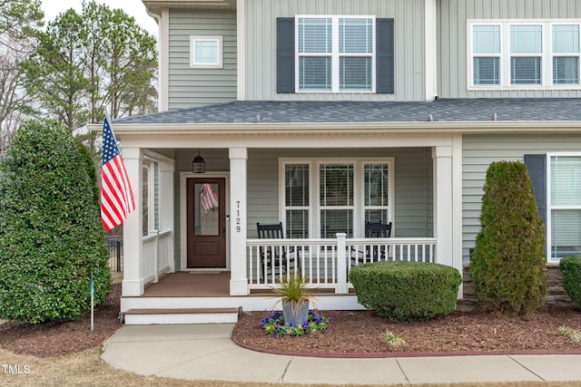 property entrance featuring covered porch and a shingled roof