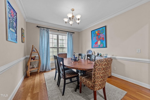 dining room featuring ornamental molding, baseboards, light wood-type flooring, and a chandelier