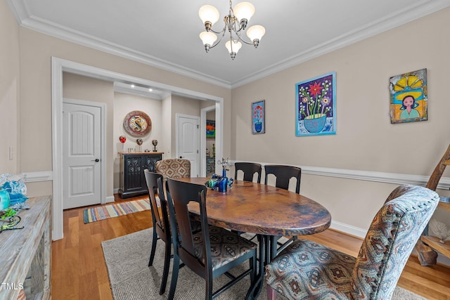 dining space with crown molding, baseboards, light wood finished floors, and a chandelier