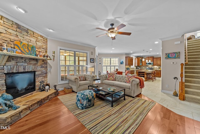 living area with crown molding, stairway, and light wood finished floors