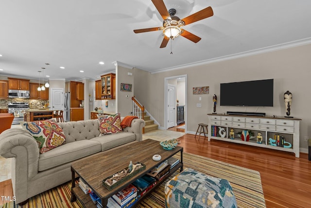 living area with stairway, baseboards, light wood-style flooring, and ornamental molding