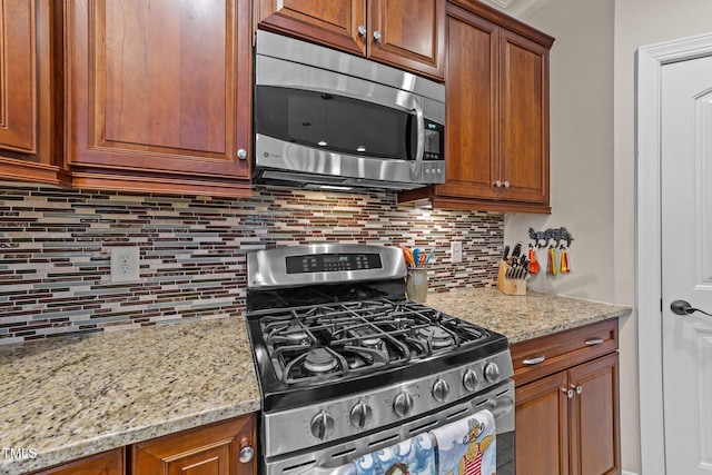 kitchen featuring decorative backsplash, light stone countertops, brown cabinets, and stainless steel appliances