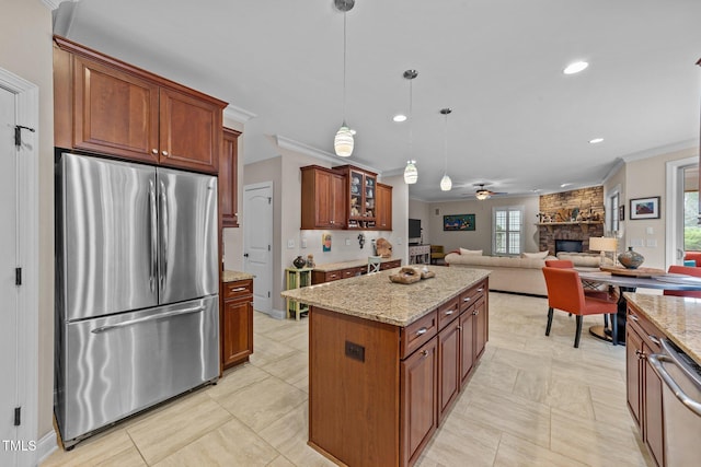 kitchen with light stone countertops, ornamental molding, a stone fireplace, stainless steel appliances, and a center island