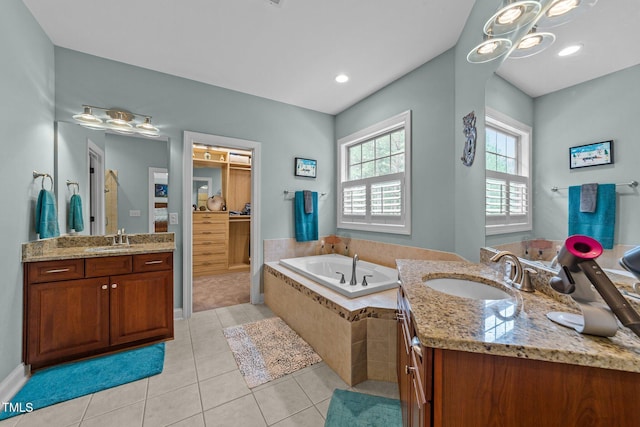 bathroom featuring a sink, two vanities, a bath, and tile patterned flooring