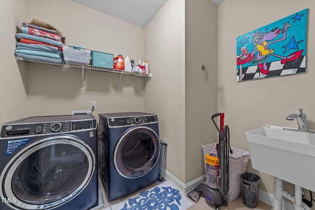 clothes washing area featuring laundry area, washing machine and dryer, baseboards, and a sink