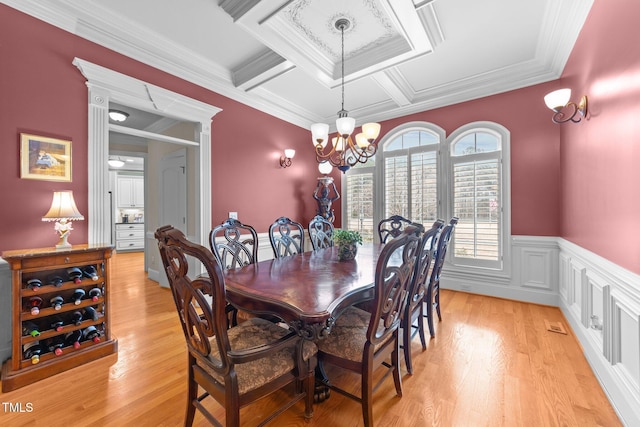 dining area featuring light hardwood / wood-style floors, ornamental molding, a chandelier, beam ceiling, and coffered ceiling