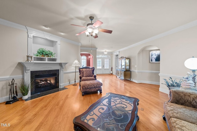 living room with ceiling fan, hardwood / wood-style flooring, a high end fireplace, and ornamental molding