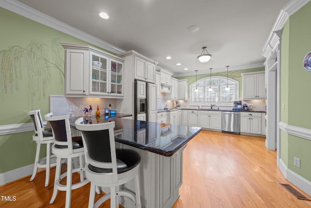 kitchen featuring dishwasher, decorative light fixtures, white cabinetry, backsplash, and a breakfast bar