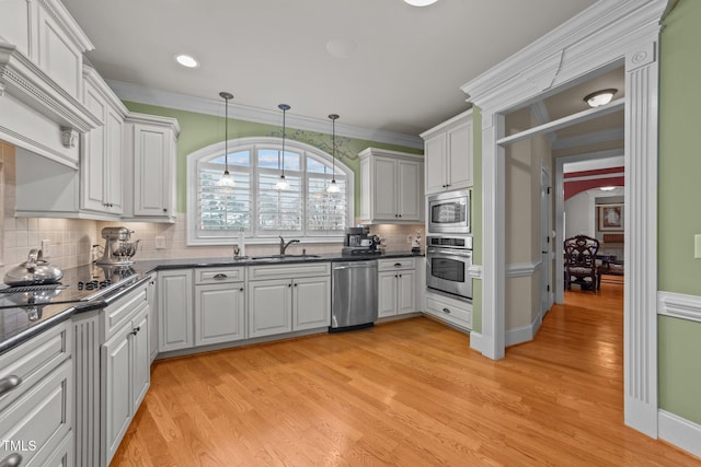 kitchen featuring pendant lighting, white cabinets, appliances with stainless steel finishes, sink, and crown molding