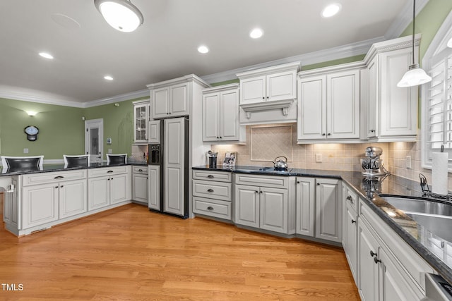 kitchen featuring white cabinets, paneled fridge, light hardwood / wood-style floors, and pendant lighting