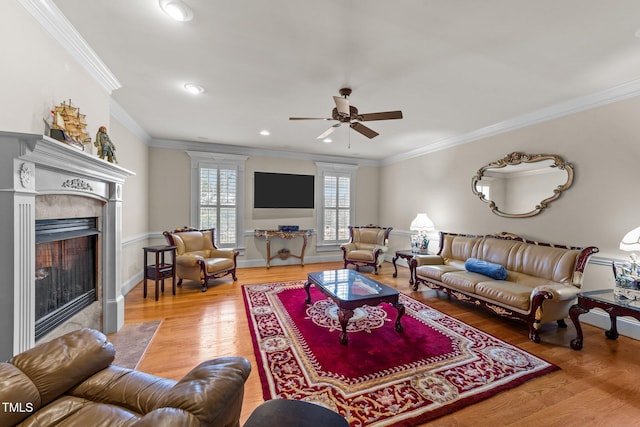 living room with a premium fireplace, ceiling fan, ornamental molding, and wood-type flooring