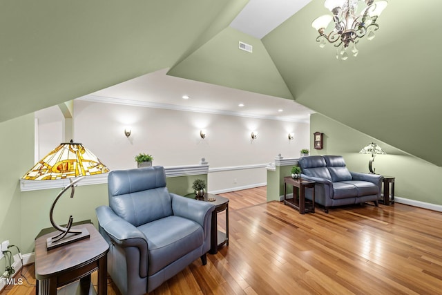 living area featuring hardwood / wood-style floors, crown molding, a notable chandelier, and vaulted ceiling