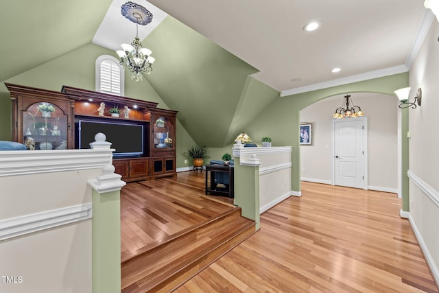 interior space featuring hardwood / wood-style flooring, lofted ceiling, crown molding, and a notable chandelier