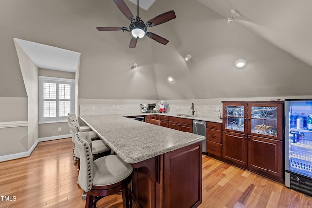 kitchen featuring decorative backsplash, a kitchen breakfast bar, kitchen peninsula, and vaulted ceiling