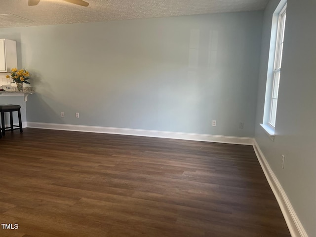 spare room with ceiling fan, a textured ceiling, and dark hardwood / wood-style floors