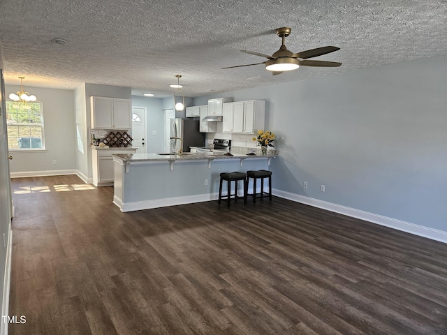 kitchen with ceiling fan with notable chandelier, decorative light fixtures, white cabinetry, stainless steel appliances, and kitchen peninsula