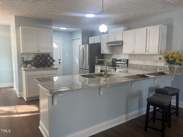 kitchen with decorative light fixtures, white cabinets, tasteful backsplash, light stone counters, and stainless steel appliances