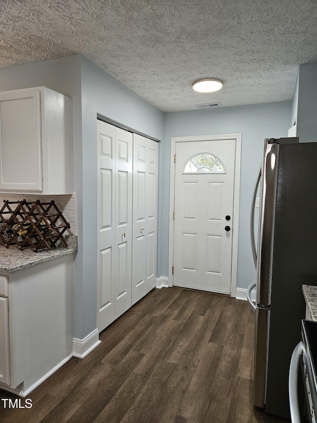 kitchen with range, a textured ceiling, white cabinetry, dark hardwood / wood-style flooring, and stainless steel fridge