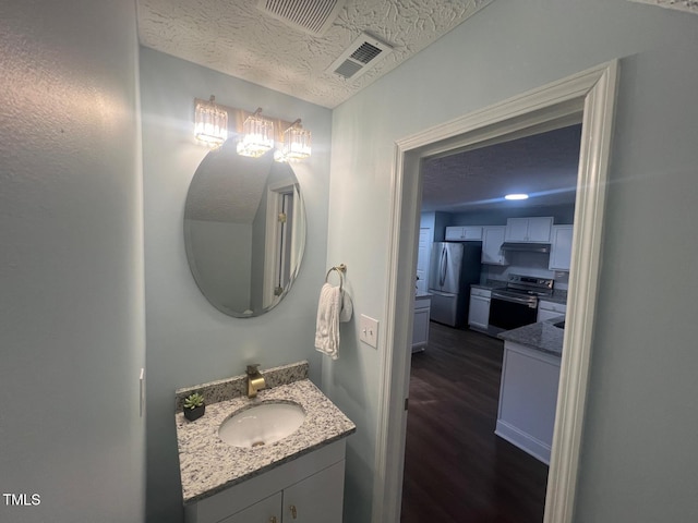 bathroom with wood-type flooring, a textured ceiling, and vanity