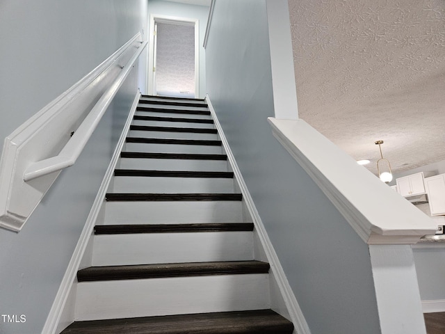 staircase featuring a textured ceiling