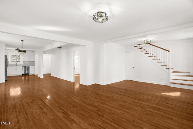 unfurnished living room with a notable chandelier and dark hardwood / wood-style flooring