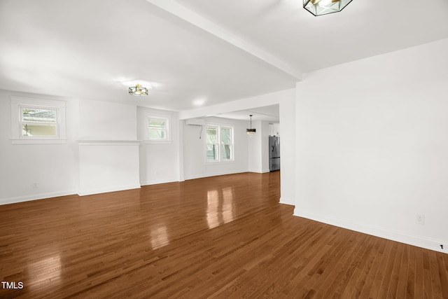 unfurnished room with beam ceiling, plenty of natural light, and dark hardwood / wood-style floors