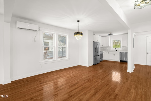 unfurnished living room with sink, dark hardwood / wood-style floors, a wall mounted AC, and a chandelier