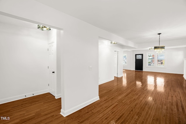 unfurnished living room with dark wood-type flooring and a notable chandelier