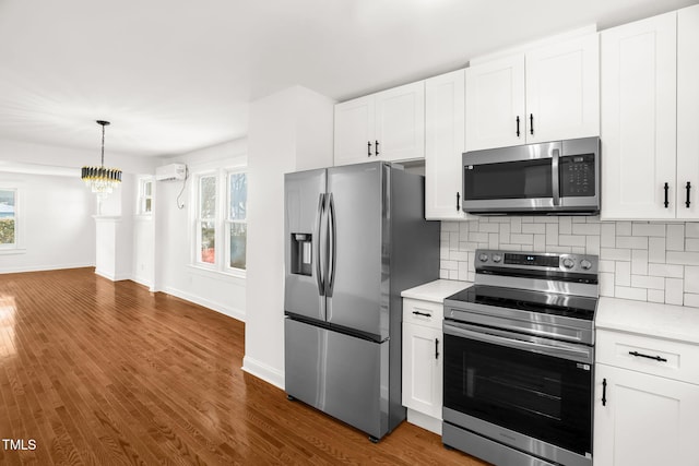 kitchen featuring appliances with stainless steel finishes, a wall mounted air conditioner, white cabinetry, backsplash, and dark hardwood / wood-style flooring